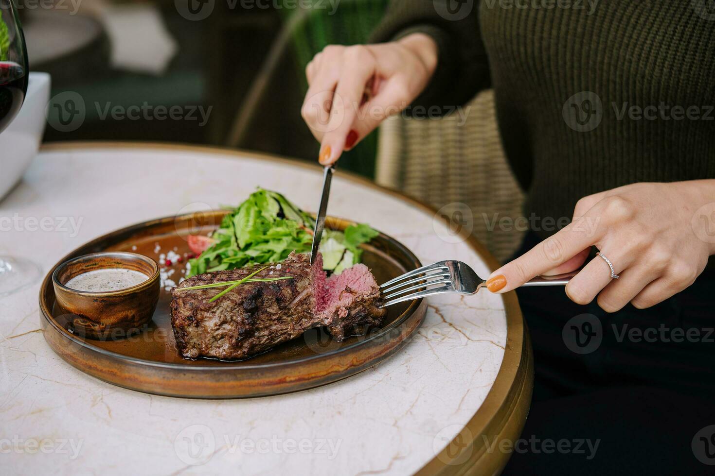 fêmea mãos dentro uma restaurante às a mesa cortar carne striploin bife foto
