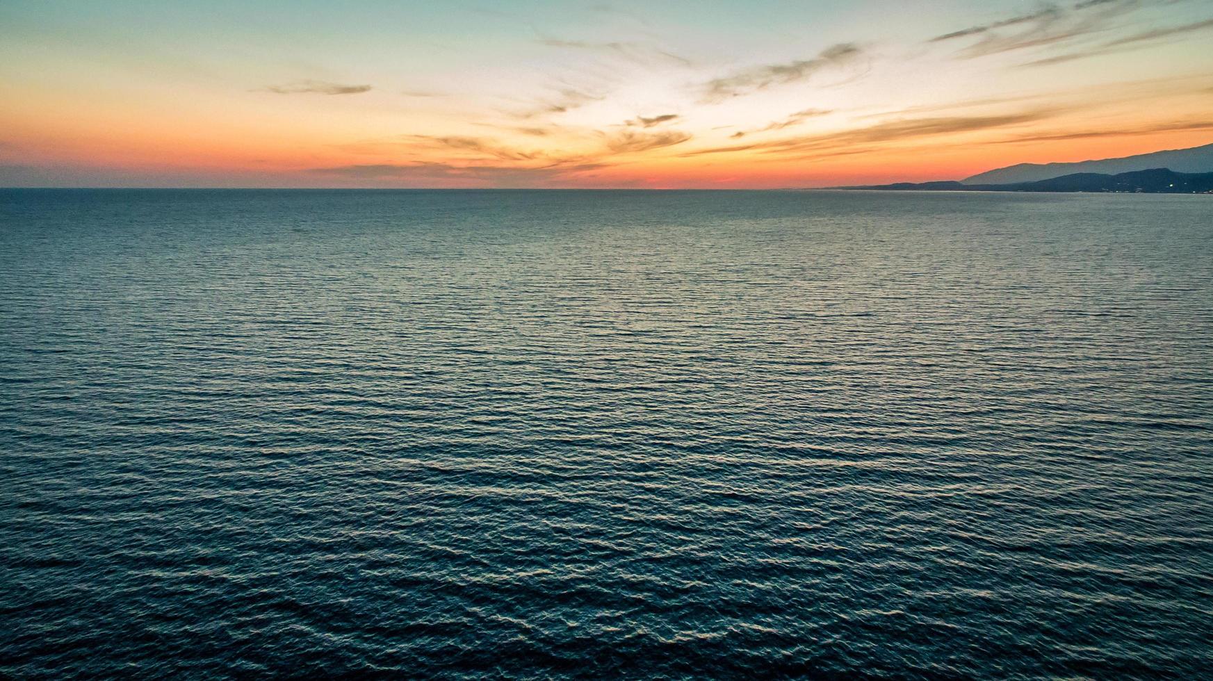 pôr do sol do voo de um pássaro sobre um mar calmo foto