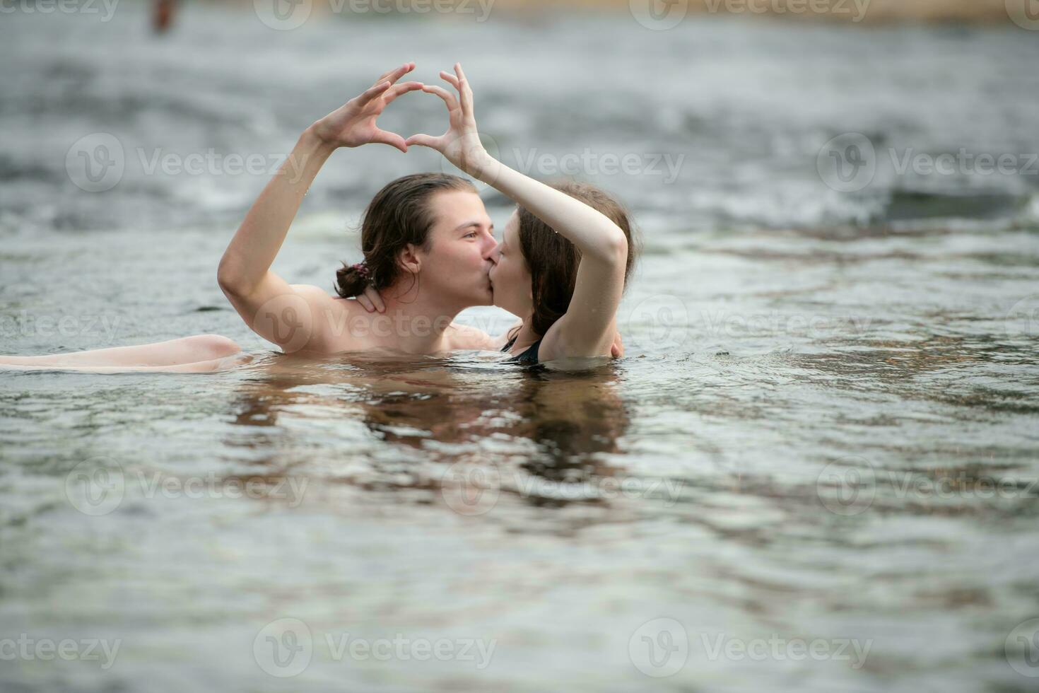 dois jovem meninas dentro a água fazer uma coração com seus mãos. foto