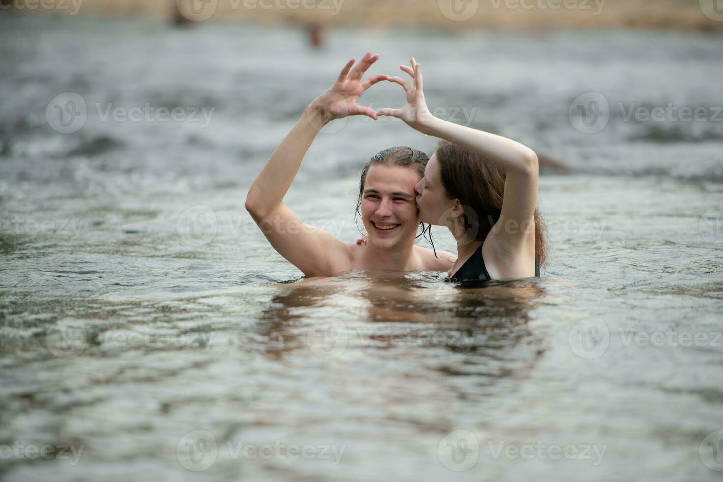 dois jovem meninas dentro a água fazer uma coração com seus mãos. foto