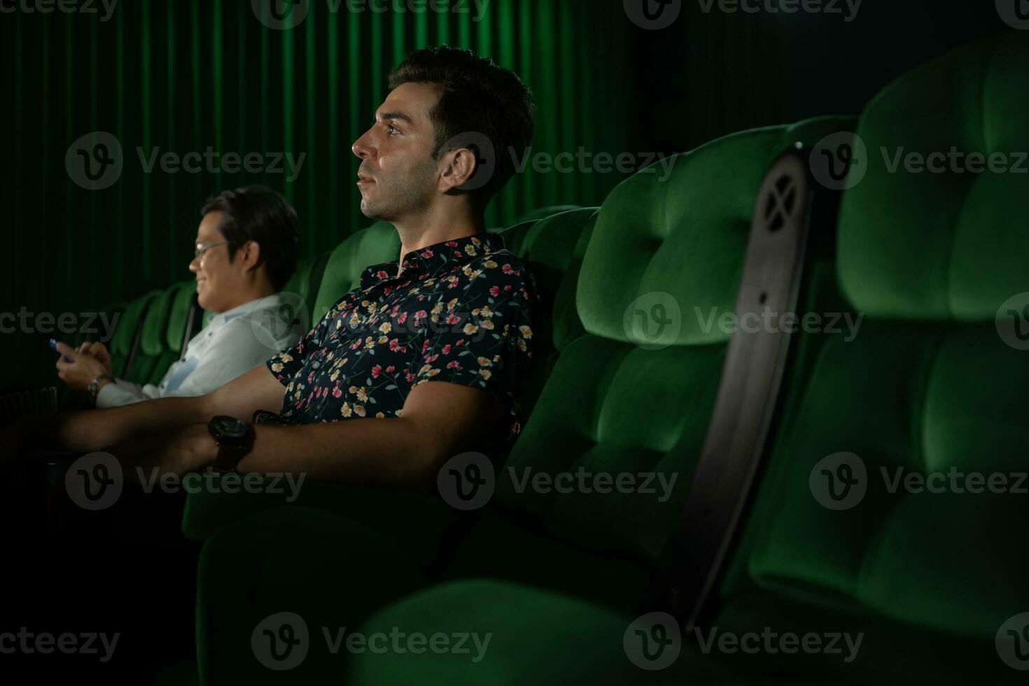 jovem casal assistindo filme dentro cinema, sentado em a verde assentos. foto