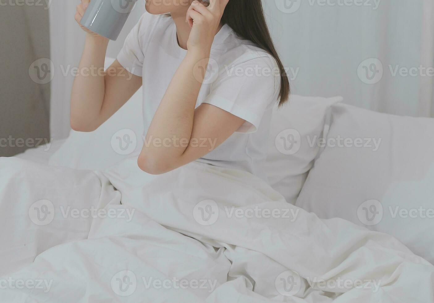 eficiente jovem milenar menina sentado em uma cama dentro a manhã, usa computador portátil computador e come croissants e bebidas café para café da manhã foto