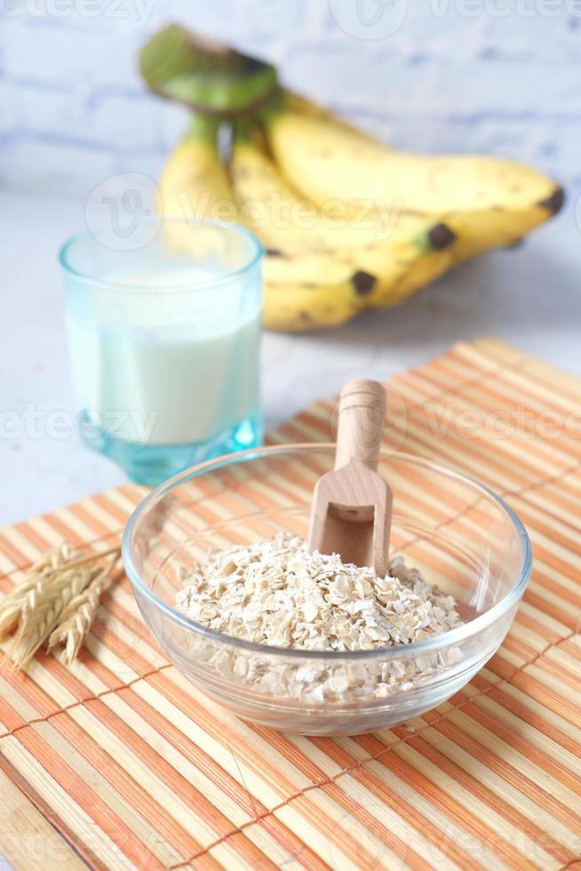 flocos de aveia, copo de leite e banana na mesa foto