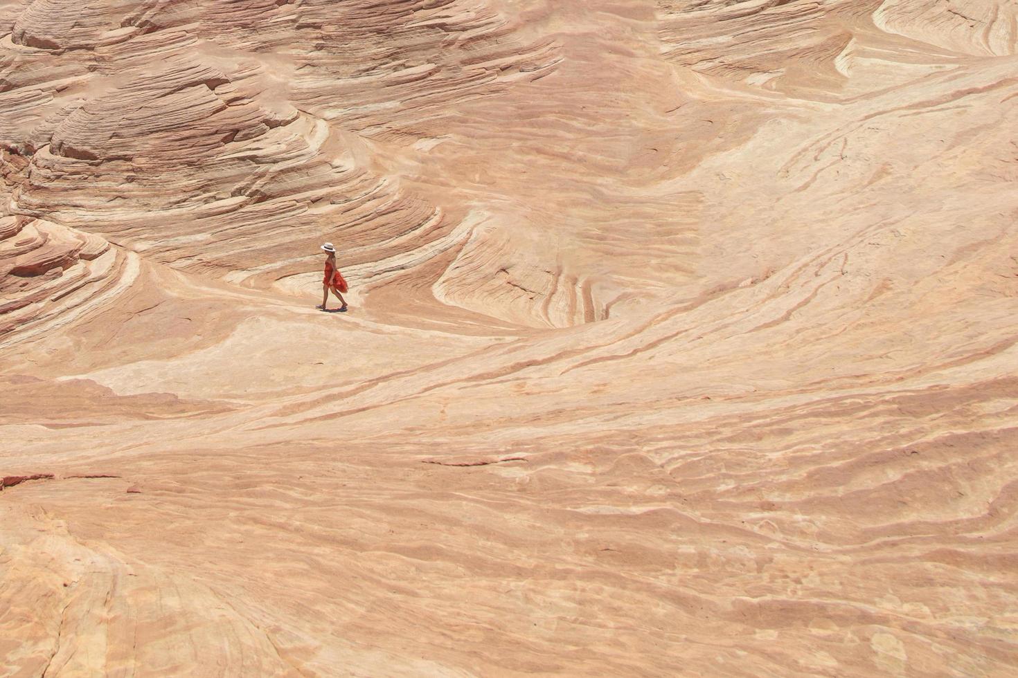 mulher caminhando sobre uma formação rochosa de arenito no deserto foto