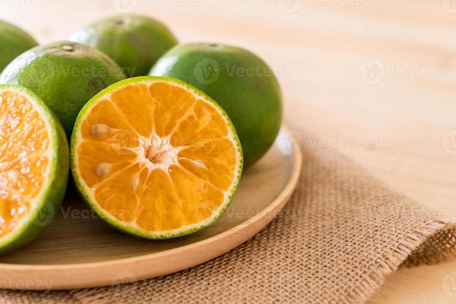 laranja fresca no prato de madeira na mesa foto