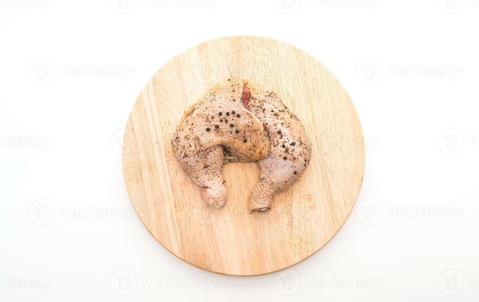 Coxa de frango marinado com molho, pimenta preta, alho e pimenta seca na tábua de madeira foto