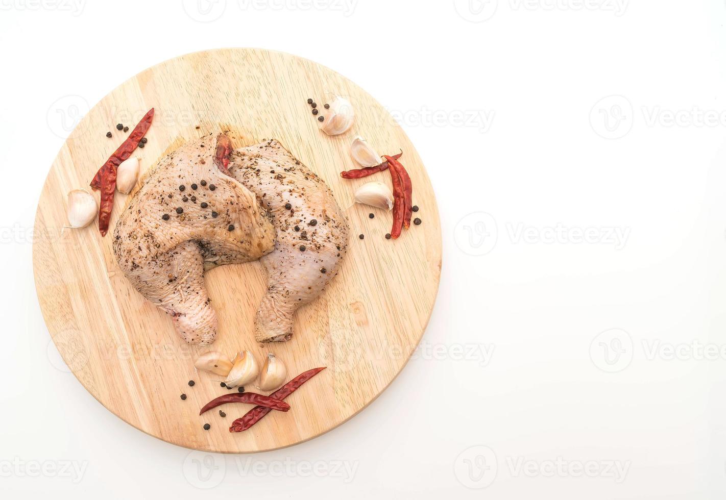 Coxa de frango marinado com molho, pimenta preta, alho e pimenta seca na tábua de madeira foto