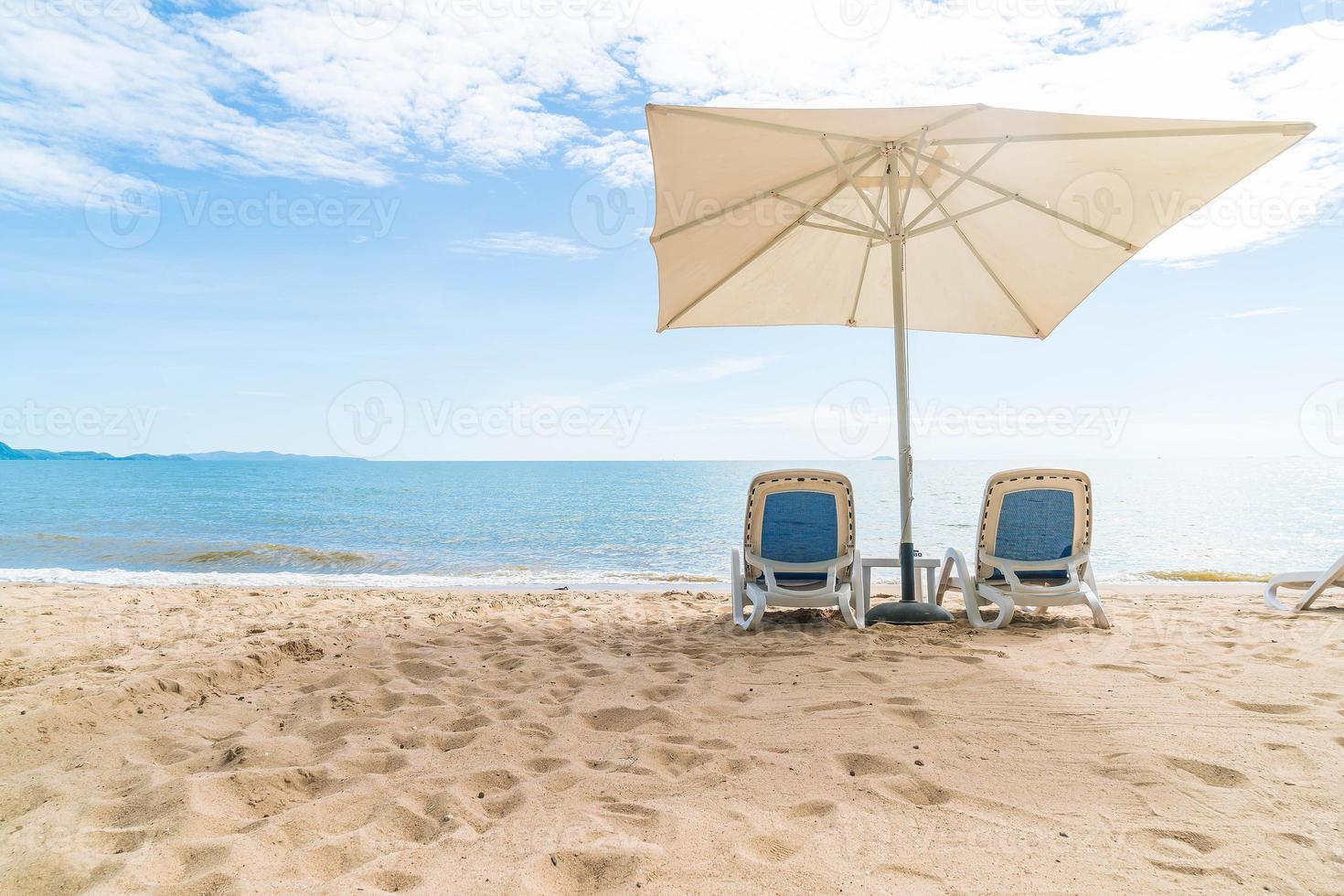 ao ar livre com guarda-sol e cadeira na bela praia tropical e mar foto