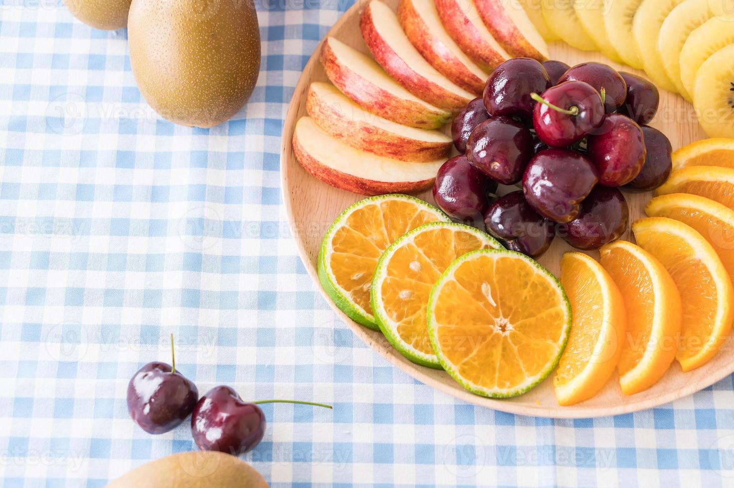 Misto de frutas fatiadas em prato de madeira foto