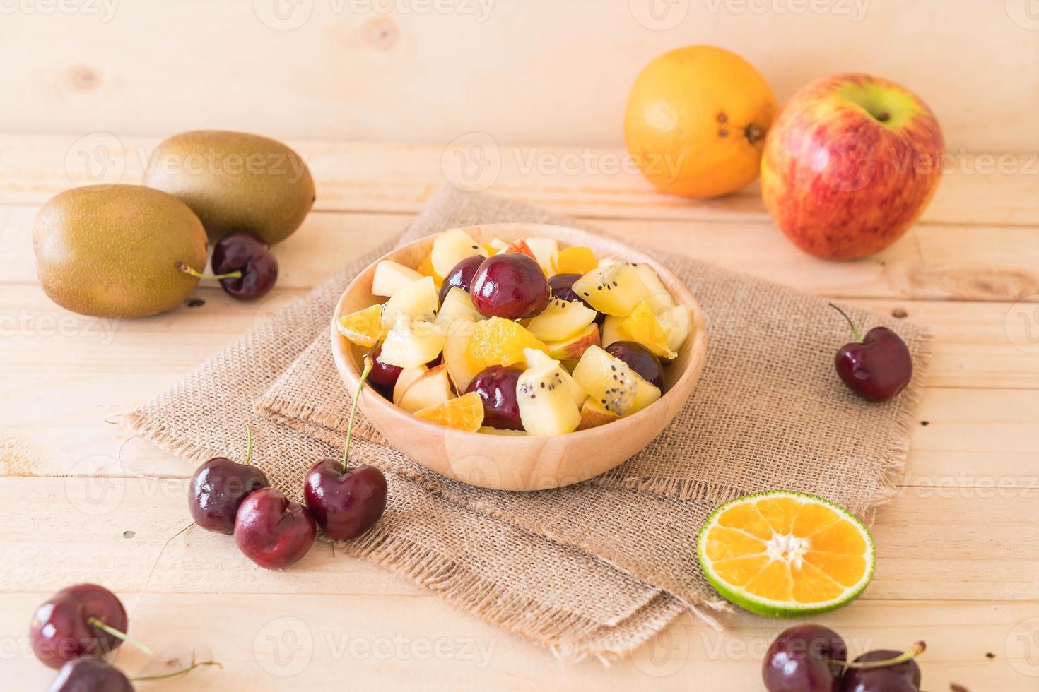 Misto de frutas fatiadas em tigela de madeira foto