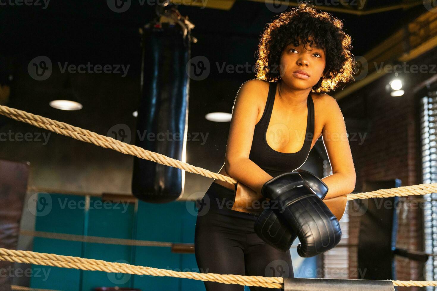 mulher lutador menina poder. africano americano mulher lutador com boxe luvas em pé em boxe anel inclinado em cordas esperando e em repouso. Forte poderoso garota. força em forma corpo exercite-se treinamento. foto