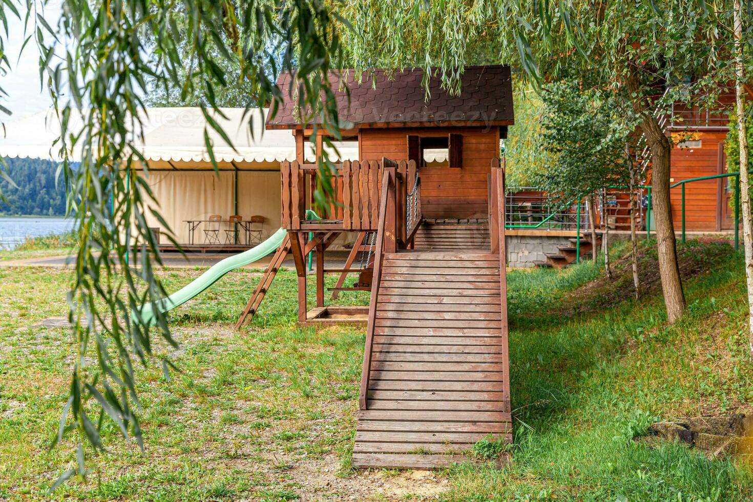 Parque infantil de madeira moderno vazio situado no quintal verde em parque público em dia de verão. terra de brinquedo engraçado para crianças. atividades de exercício urbano para crianças ao ar livre. conceito de infância de bairro. foto