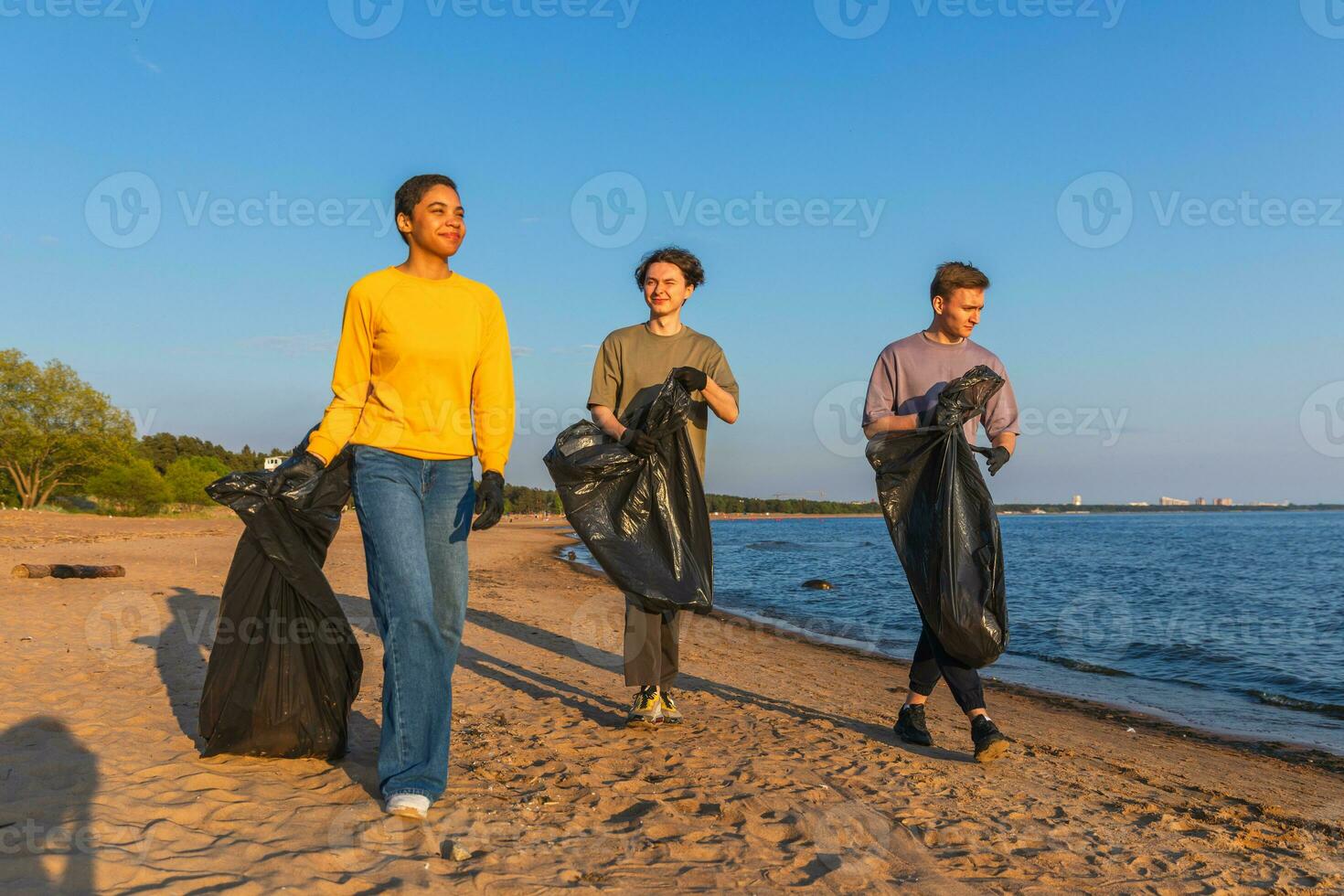 terra dia. voluntários ativistas coleta lixo limpeza do de praia costeiro zona. mulher mans com Lixo dentro lixo saco em oceano costa. de Meio Ambiente conservação costeiro zona limpeza. borrado vídeo. foto