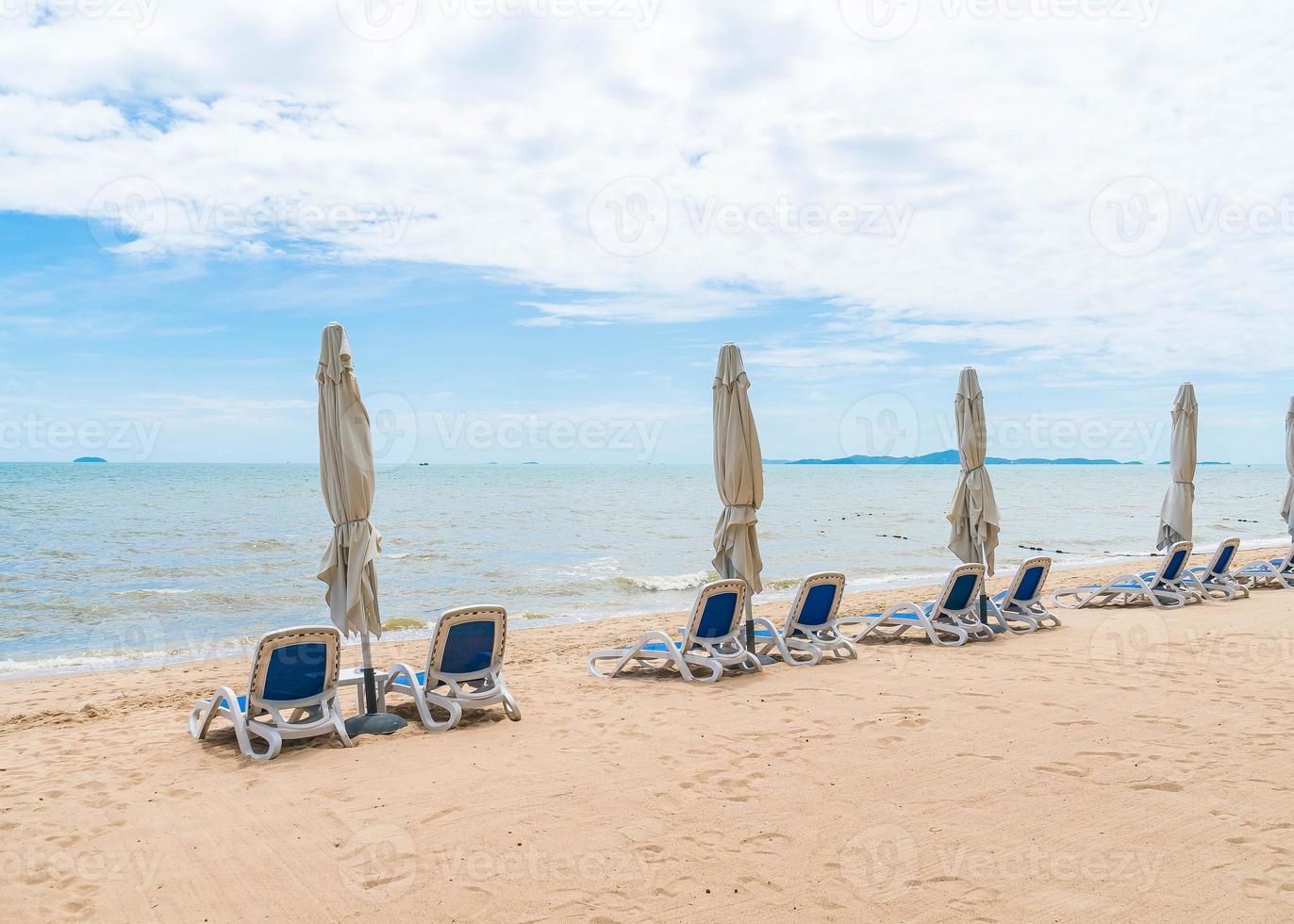 ao ar livre com guarda-sol e cadeira na bela praia tropical e mar foto