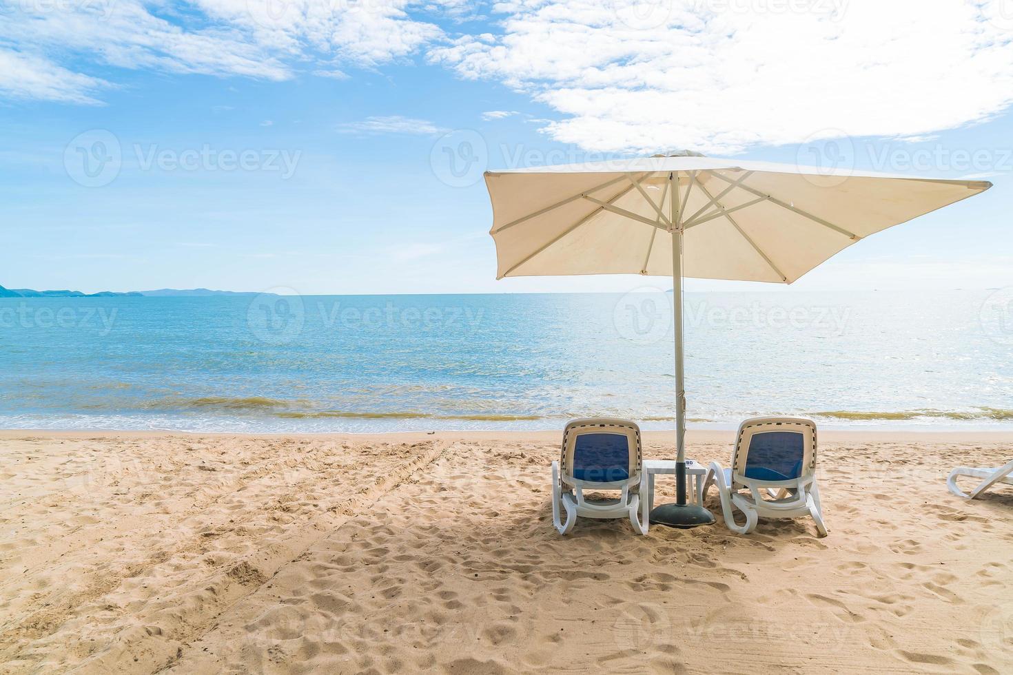 ao ar livre com guarda-sol e cadeira na bela praia tropical e mar foto