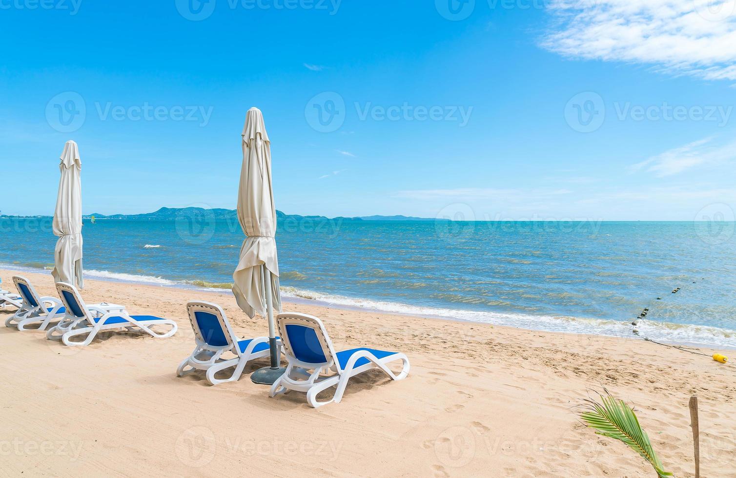 ao ar livre com guarda-sol e cadeira na bela praia tropical e mar foto