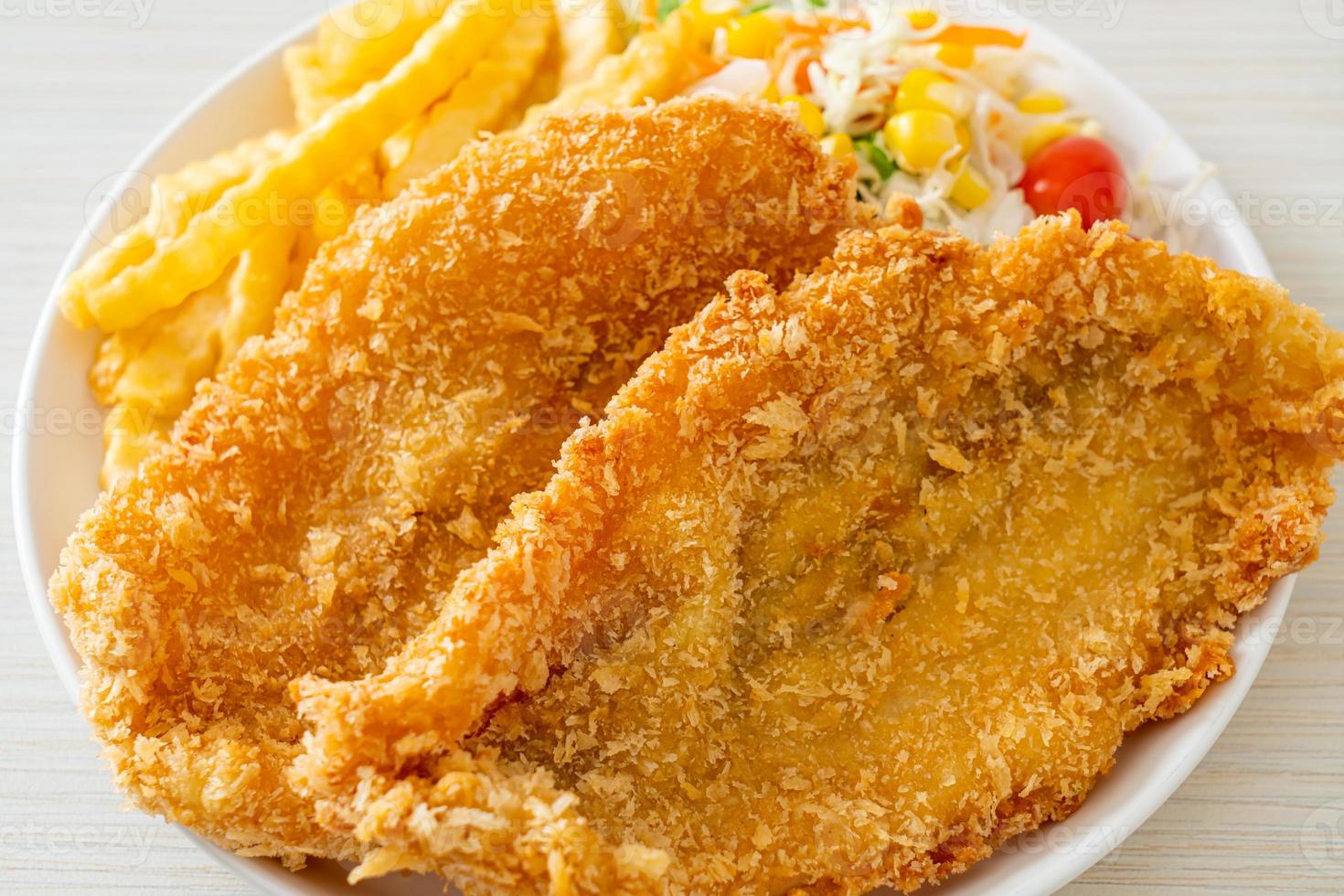 peixe com batatas fritas com mini salada no prato branco foto
