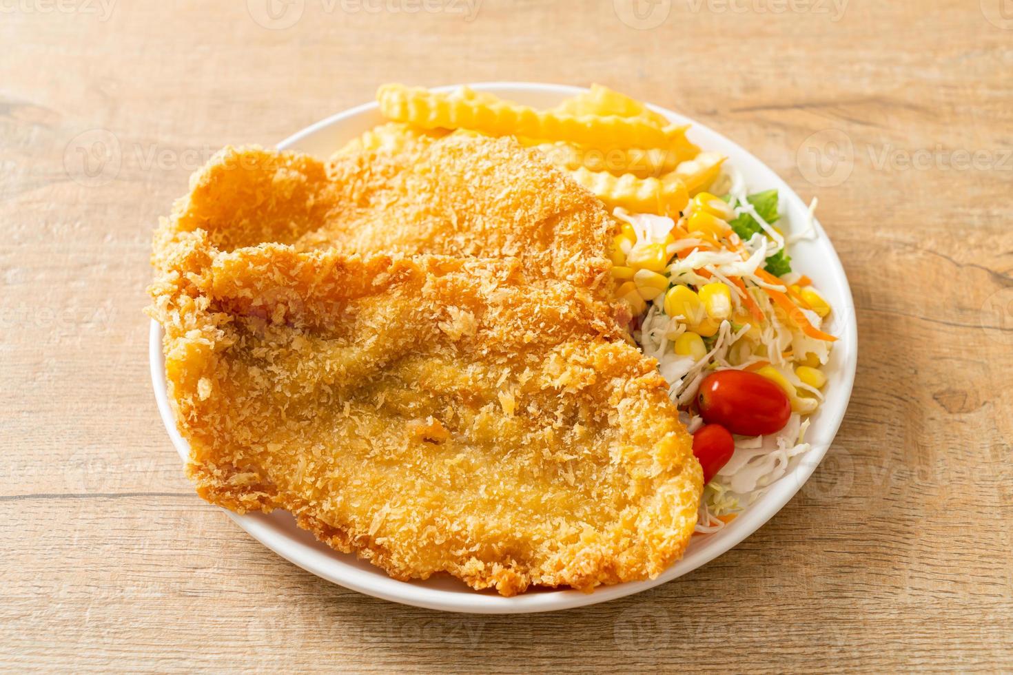 peixe com batatas fritas com mini salada no prato branco foto