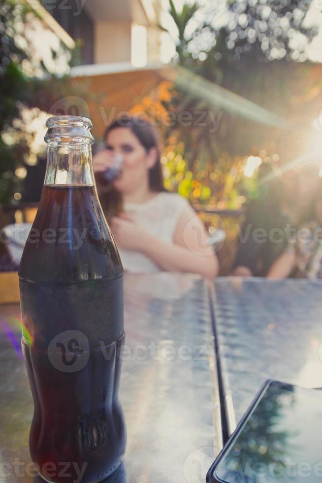 garrafa de vidro de refrigerante de cola gelado na mesa de metal foto