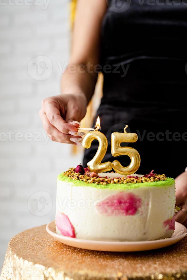 mulher caucasiana em vestido de festa preto acendendo velas no bolo de aniversário foto