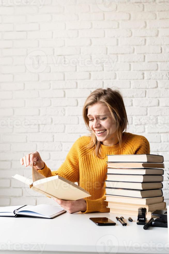 jovem sorridente com suéter amarelo lendo um livro e rindo foto