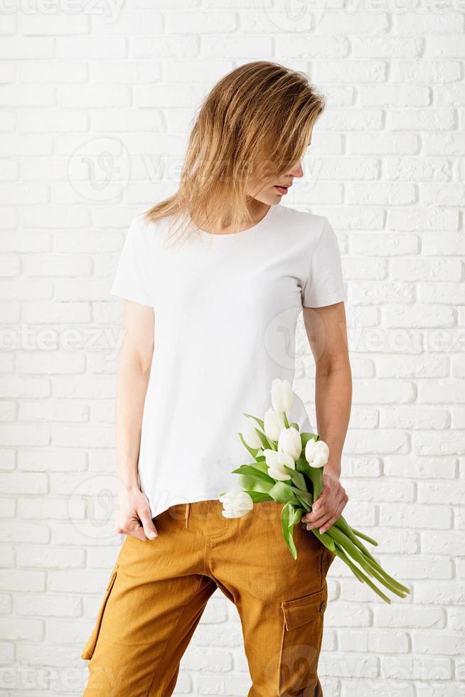 jovem vestindo uma camiseta branca em branco segurando flores de tulipas foto