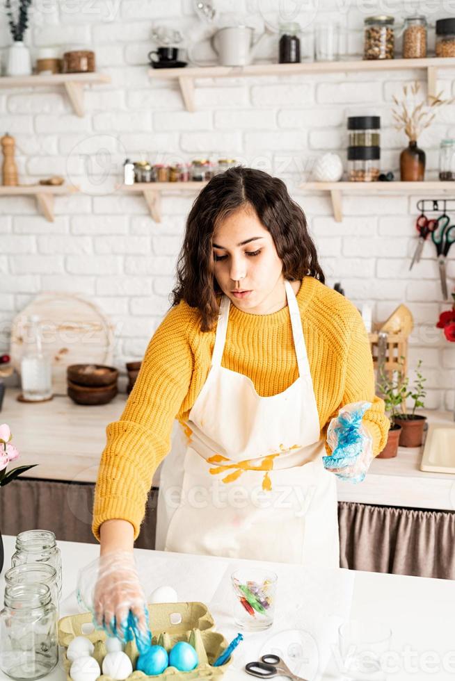 mulher colorindo ovos de páscoa de azul na cozinha foto