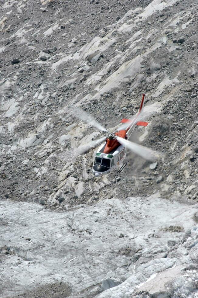 uma helicóptero é vôo sobre uma rochoso montanha foto