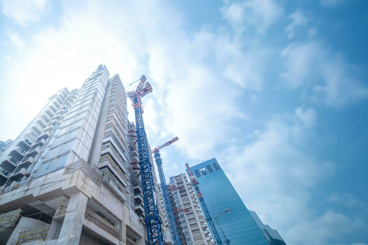 Alto subir construção debaixo construção. a local com guindastes contra azul céu. foto