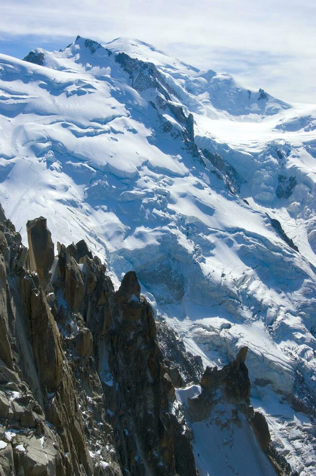 dois pessoas estão caminhada acima uma montanha com neve coberto montanhas foto