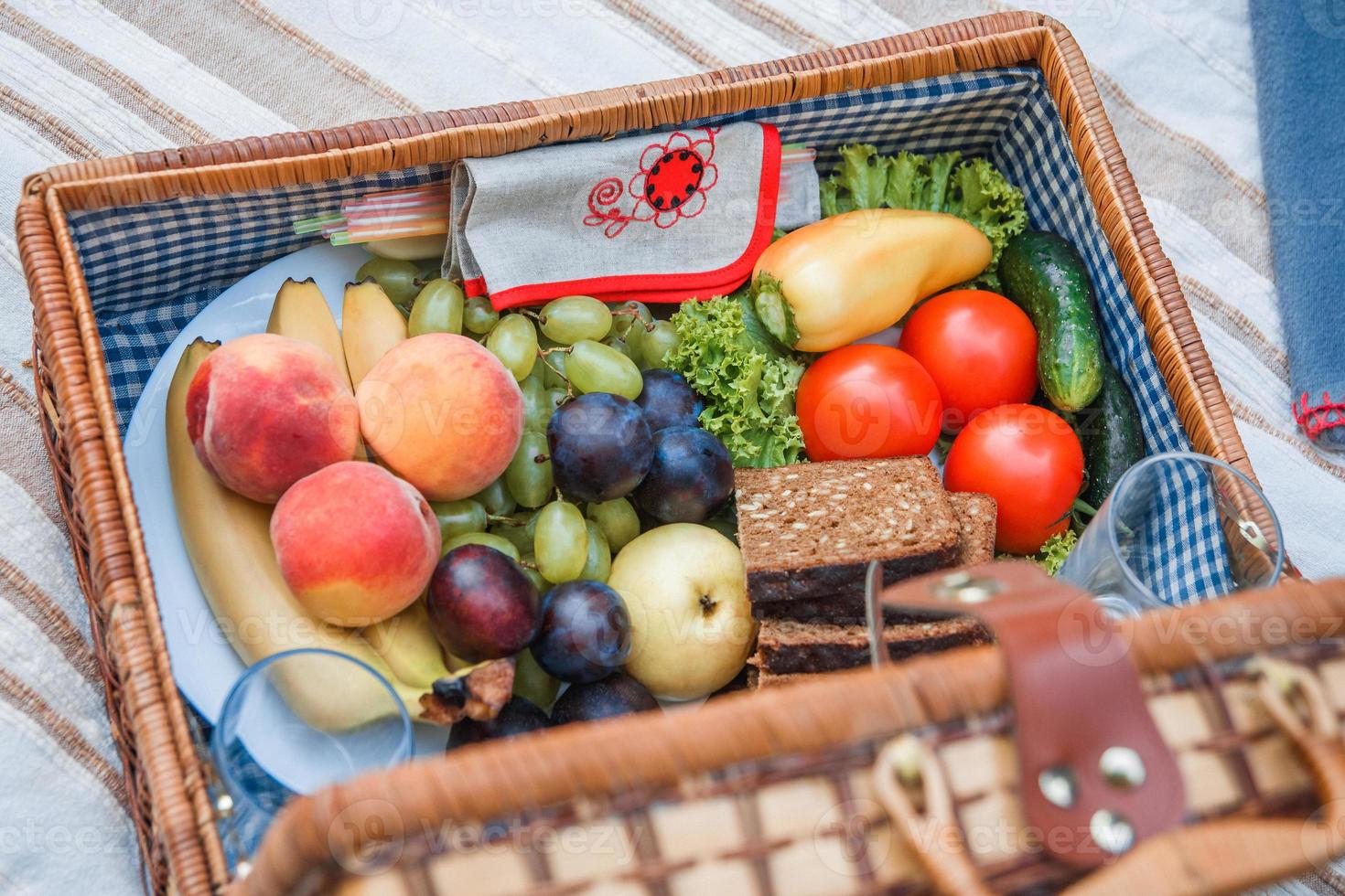 cesta de piquenique com frutas e pão de perto foto