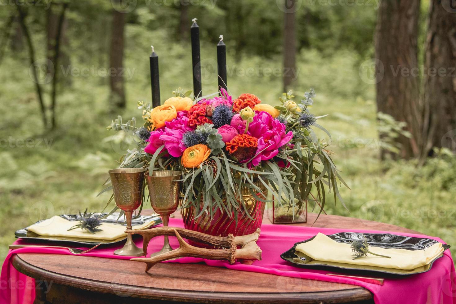mesa de madeira decorada com flores, velas, utensílios foto