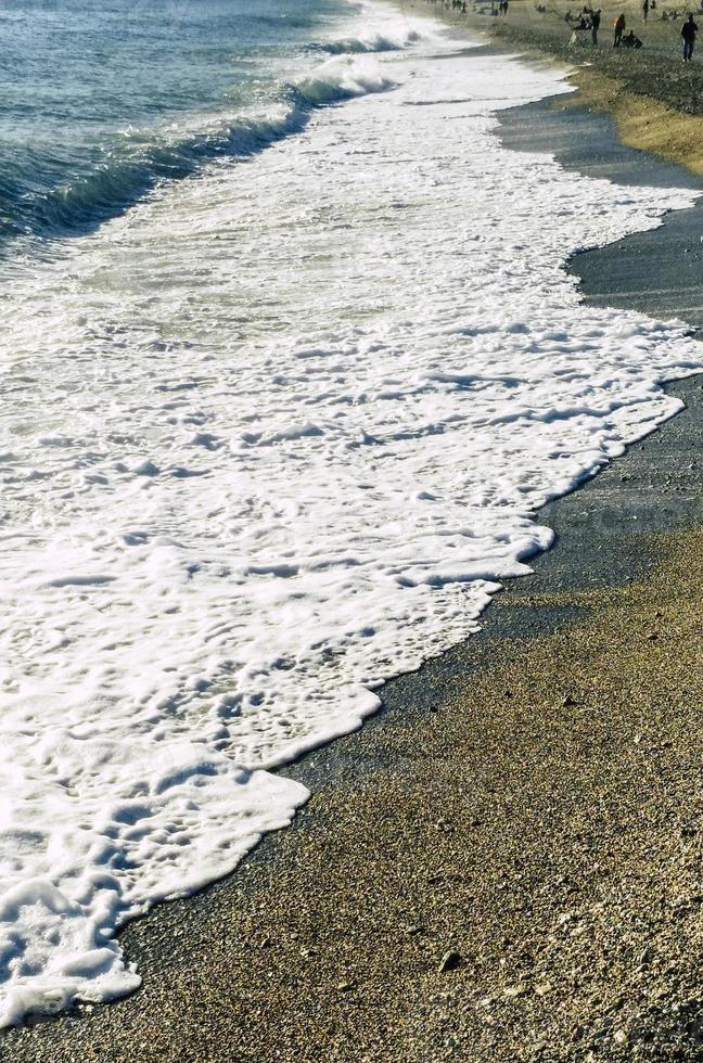 praia na ligúria com ondas do mar e areia foto