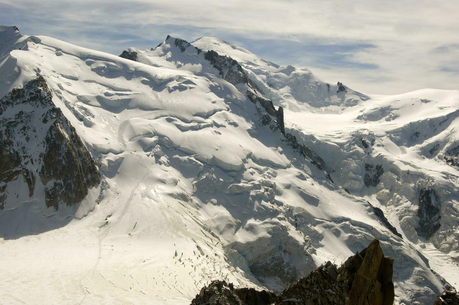 dois pessoas estão caminhada acima uma montanha com neve coberto montanhas foto