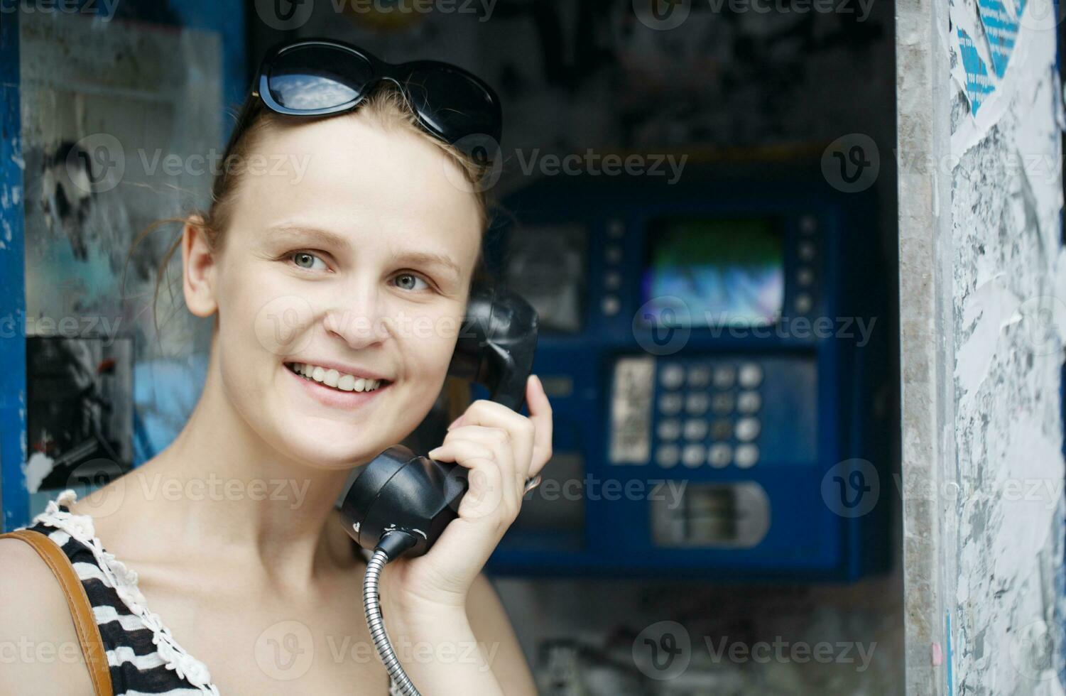 atraente mulher usando uma público Telefone foto