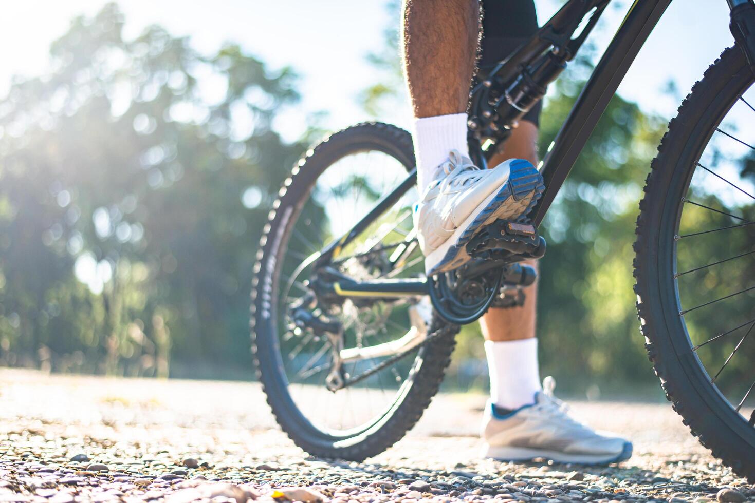 uma perspectiva ciclistas em um caminho rochoso ao pôr do sol com foco nos sapatos foto