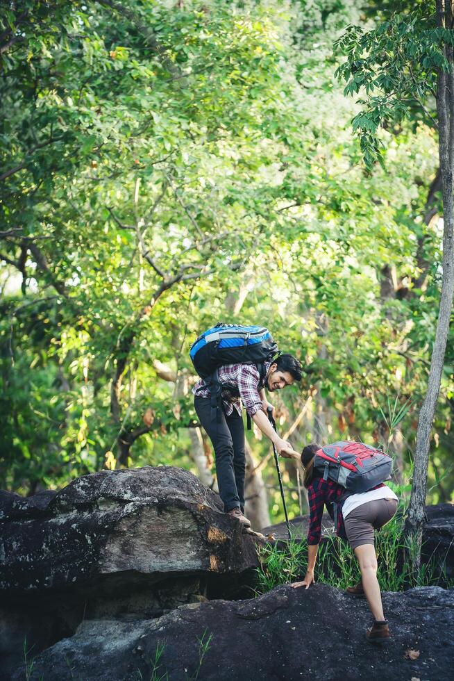 mulher alpinista recebendo ajuda na caminhada sorrindo feliz superando o obstáculo. foto