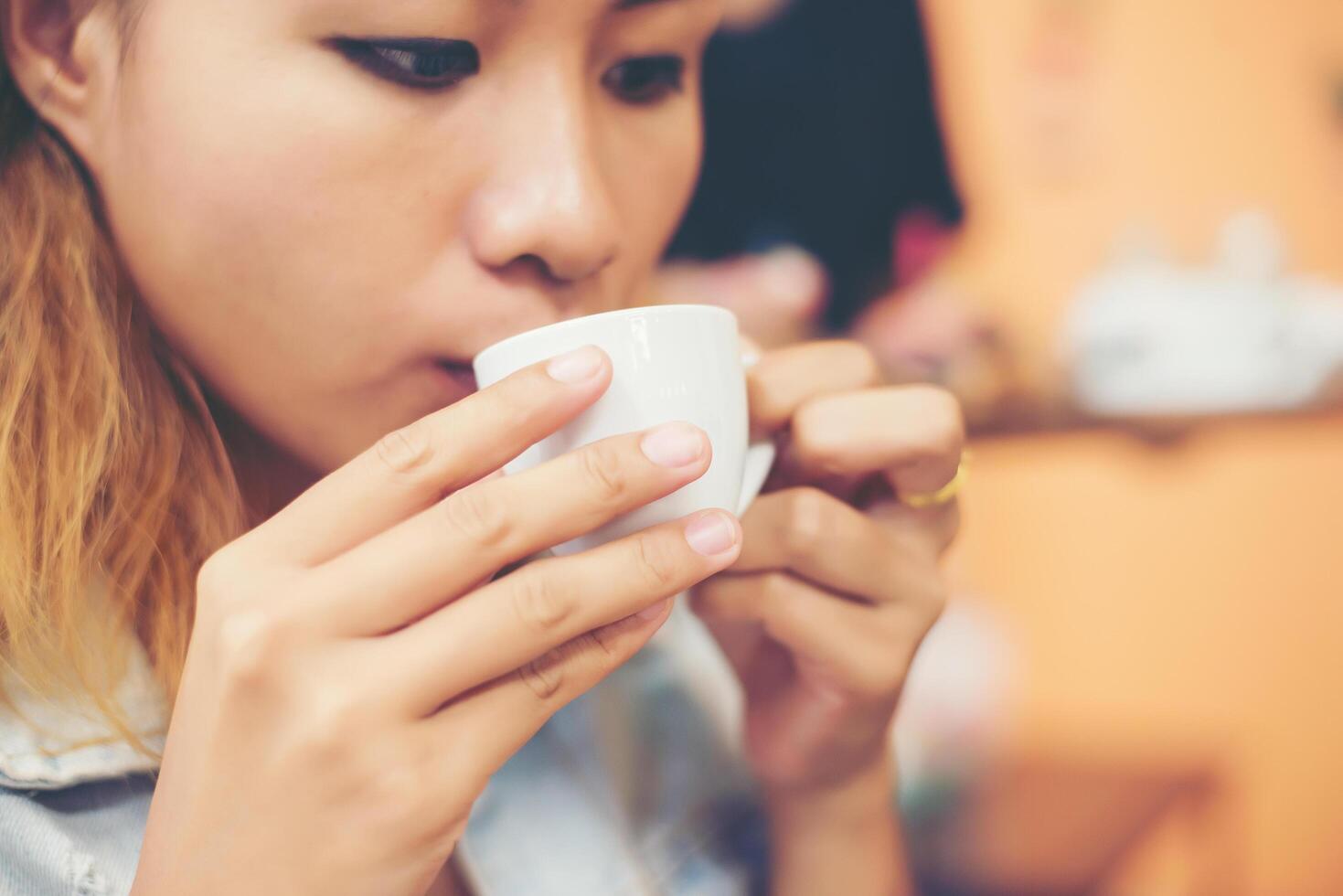 jovem mulher bonita sentada em um café bebendo chá verde quente. foto