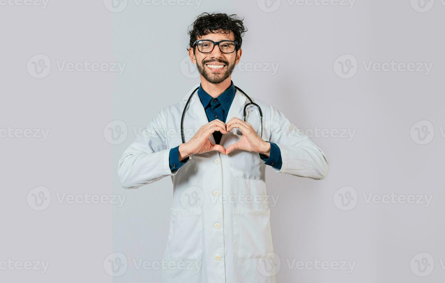 jovem médico fazer coração forma isolado. bonito médico fazer coração gesto com mãos. feliz médico apontando dedos baixa foto