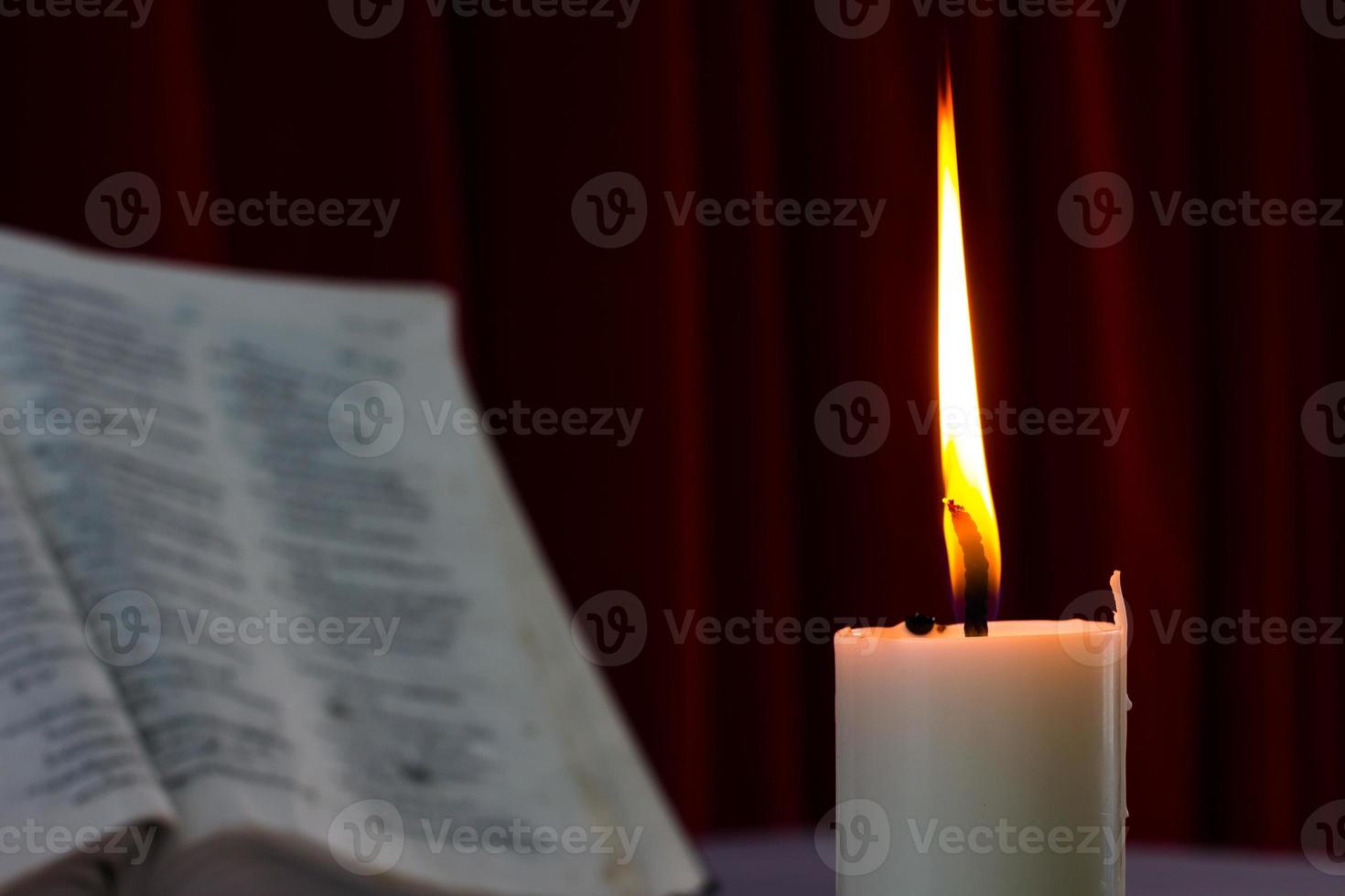 bíblia aberta em uma mesa com vela foto