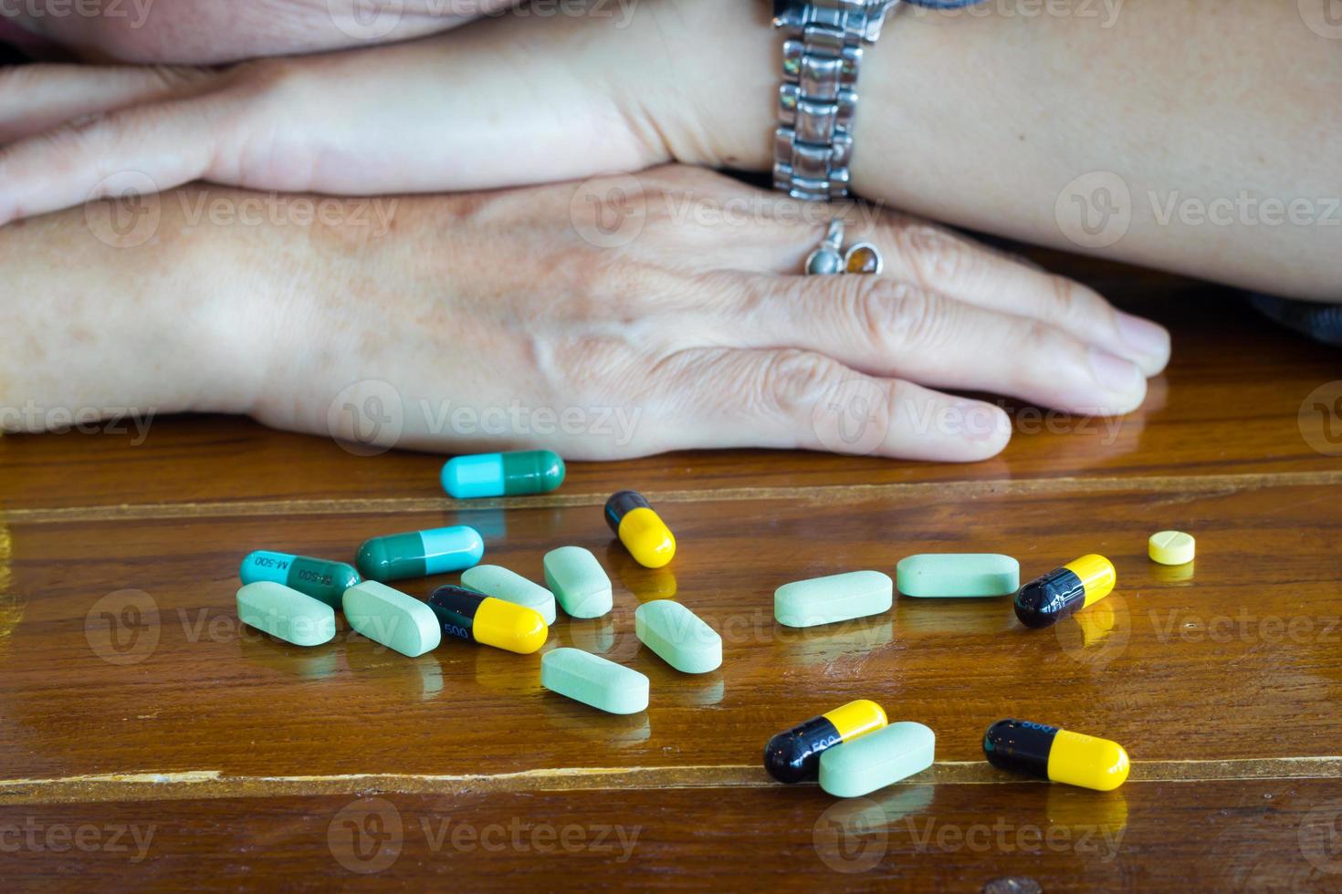 medicamentos em uma mesa de madeira com as mãos de uma mulher foto