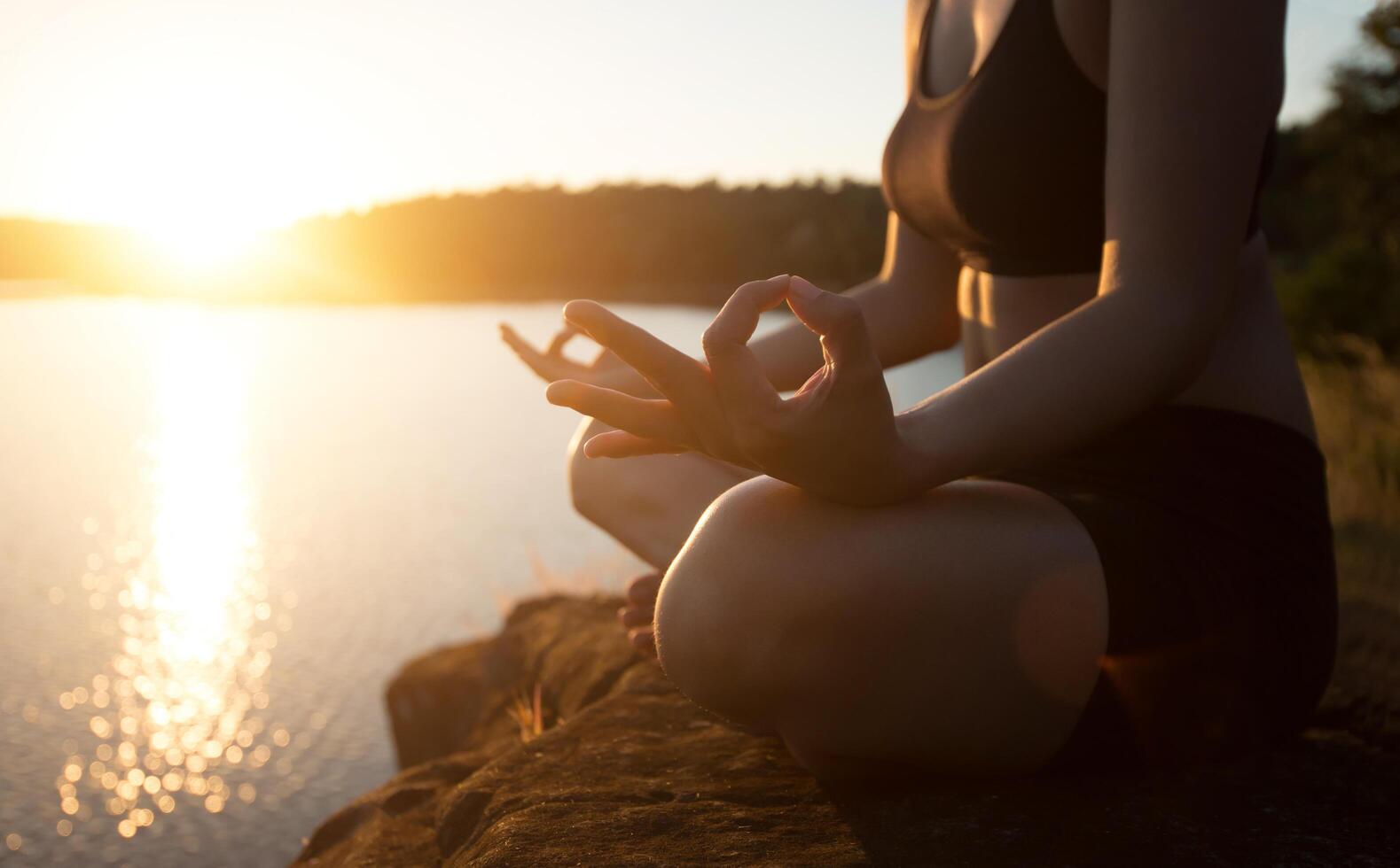 jovem mulher saudável está praticando ioga no lago da montanha durante o pôr do sol. foto