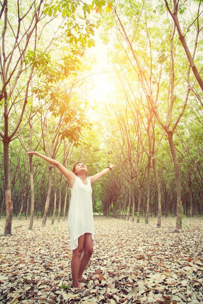 bela jovem levantou os braços, apreciando o fresco na floresta verde. foto