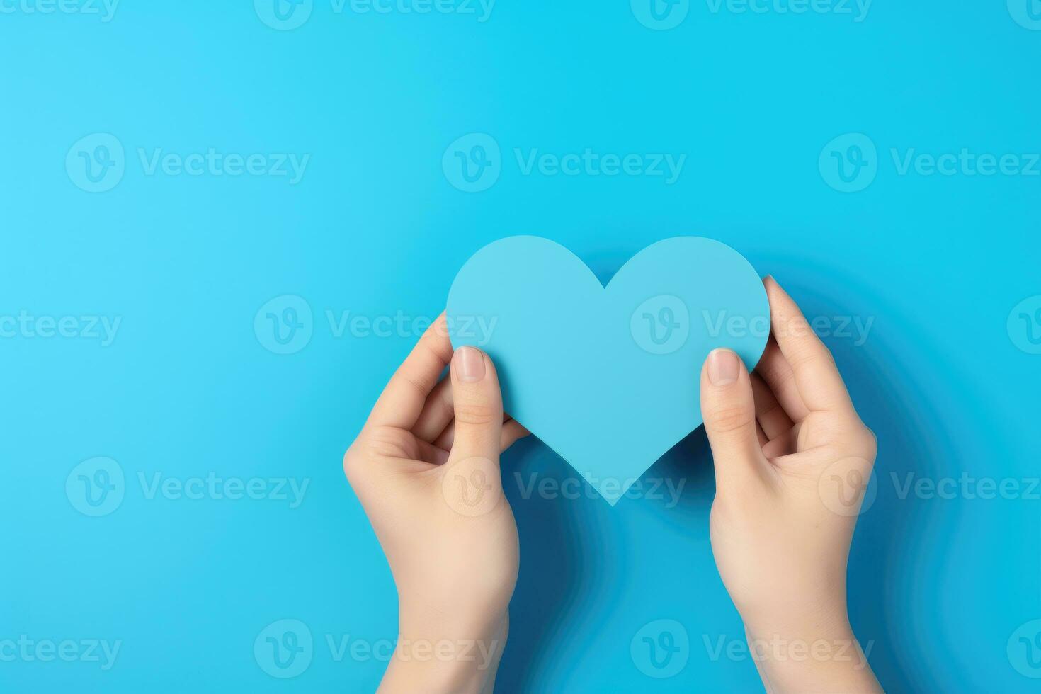 fêmea mãos segurando azul papel coração em azul fundo, topo Visão com cópia de espaço foto