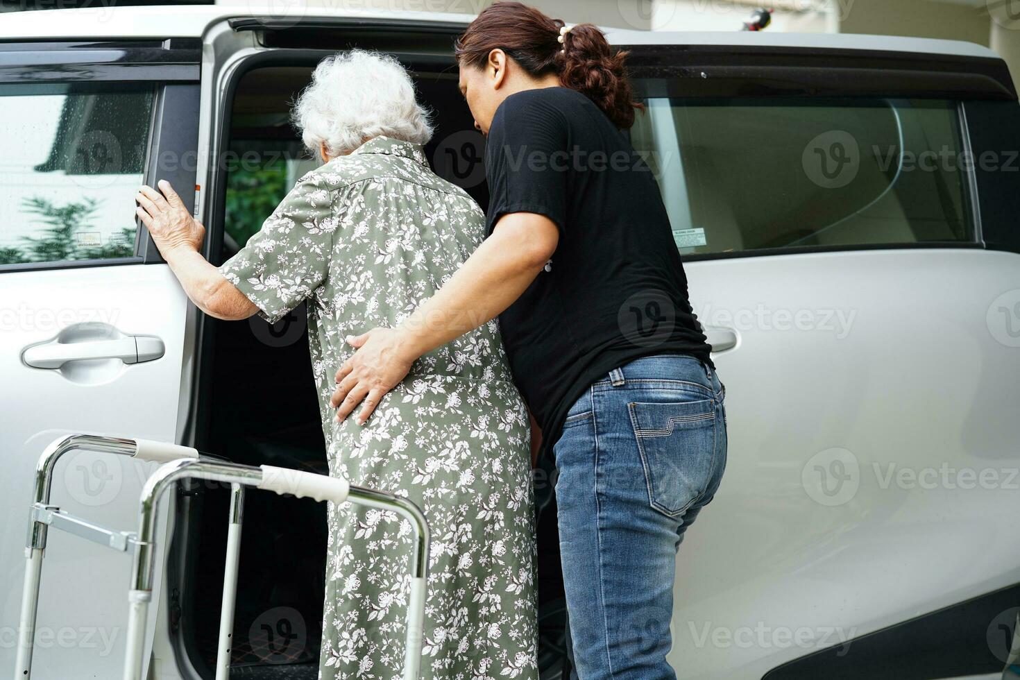 cuidador ajuda paciente idosa asiática com deficiência entrar em seu carro, conceito médico. foto