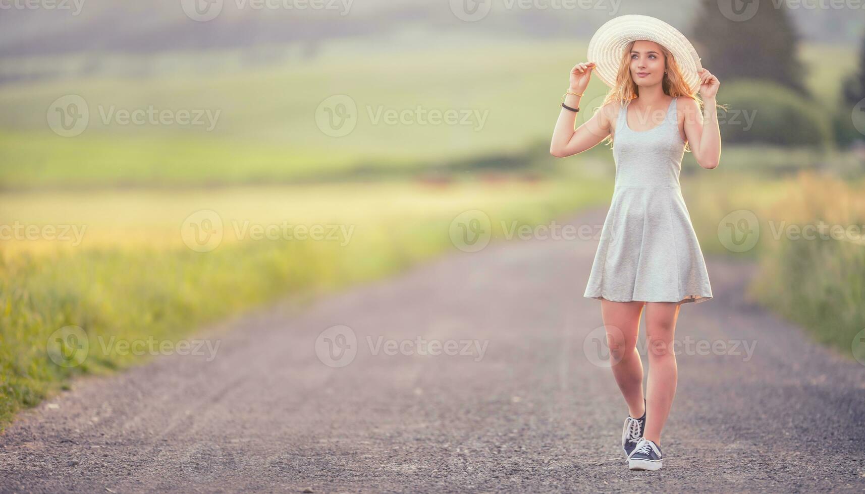 jovem mulher dentro chapéu caminhando em campo estrada. verão romântico imagem foto