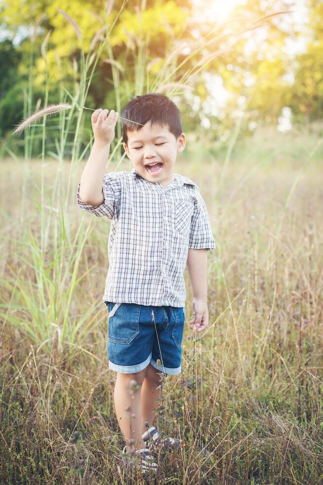 menino asiático feliz brincando ao ar livre. bonito rapaz asiático em campo. foto