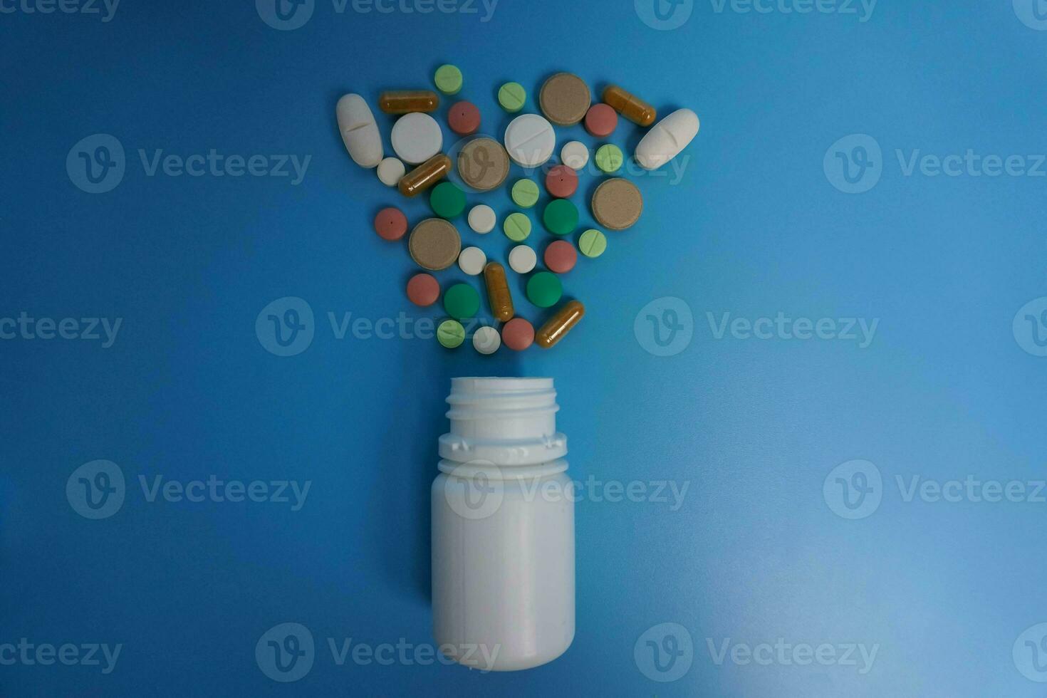 topo Visão sortido colorida farmacêutico remédio pílulas, comprimidos e cápsulas e branco garrafas em azul fundo. cópia de espaço para texto foto