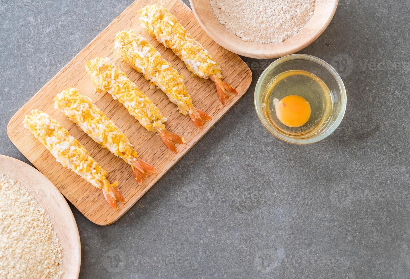 Camarões fritos em massa na tábua de madeira com ingredientes foto