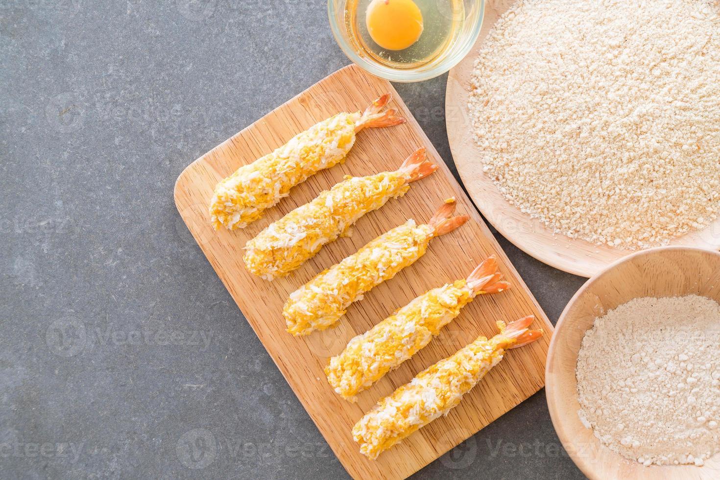 Camarões fritos em massa na tábua de madeira com ingredientes foto